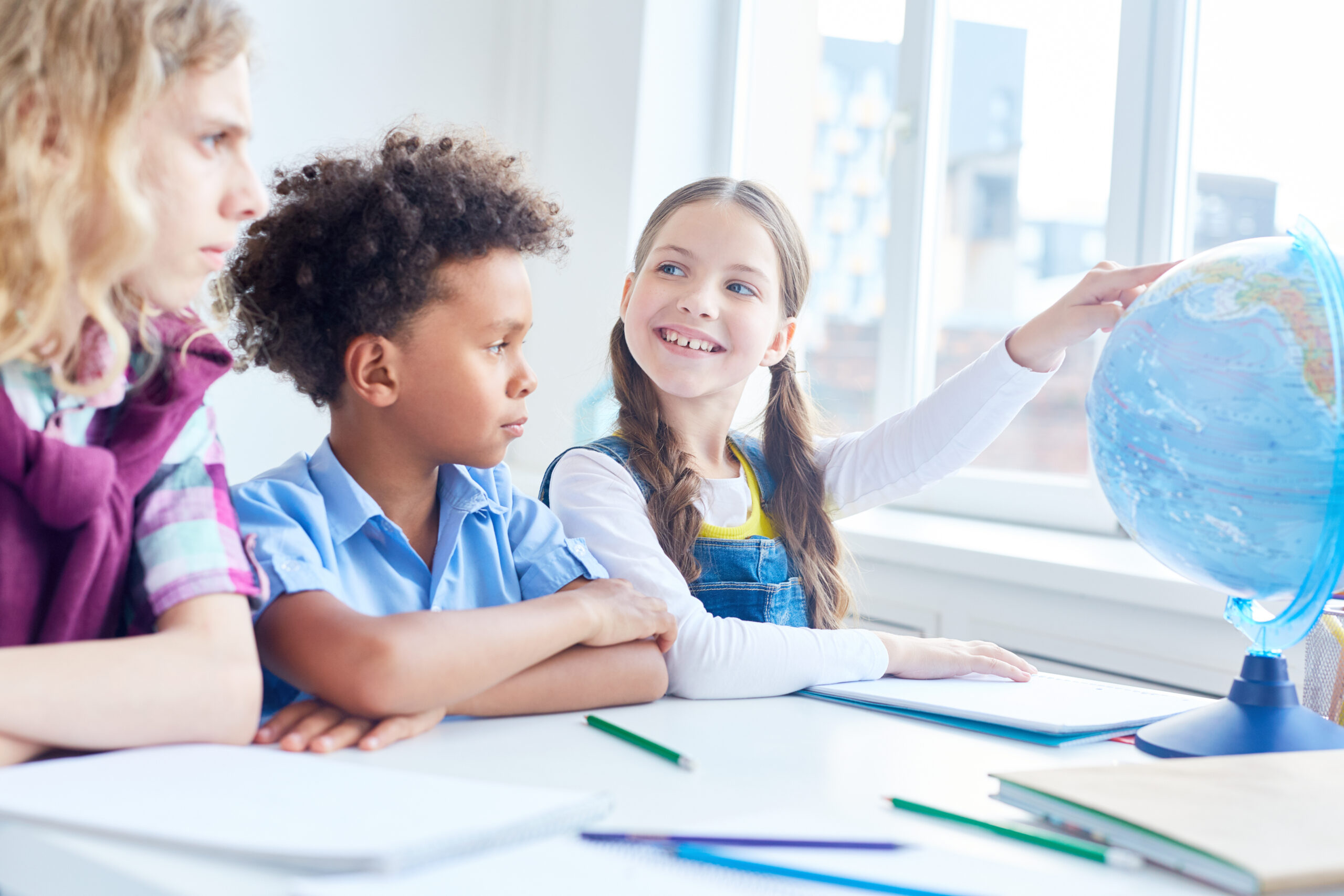 Teacher giving a geography lesson to children in a classroom